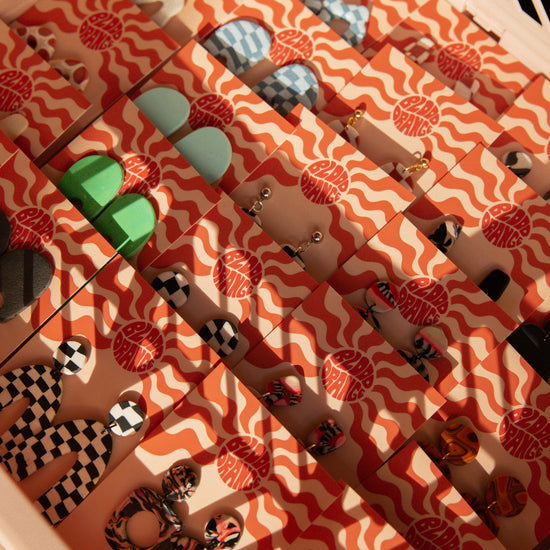 Rows of earring display cards with various coloured earrings placed on them sitting in the sunlight